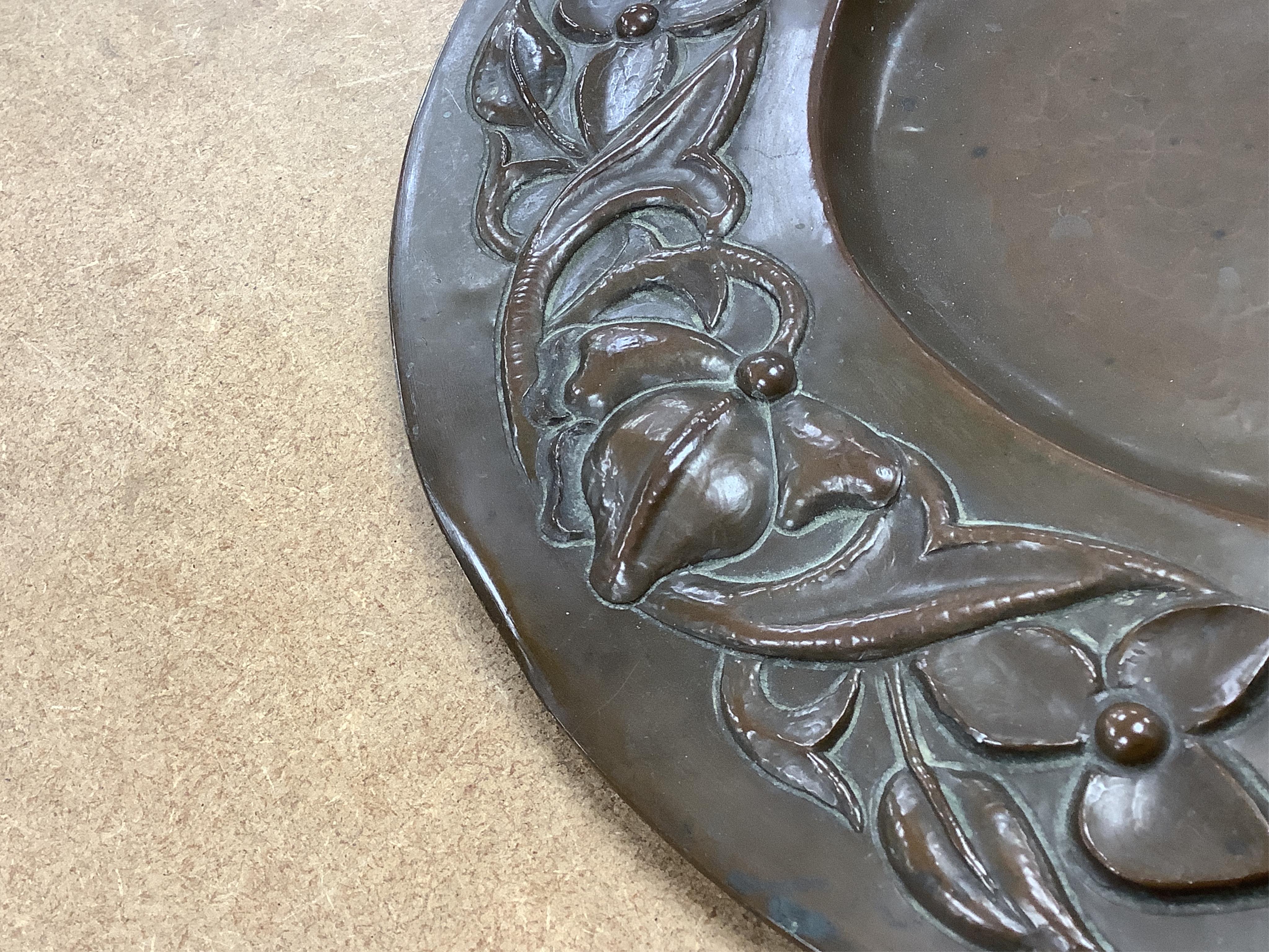 An Arts and Crafts embossed copper dish, in the manner of John Pearson, inlaid with Ruskin cabochons, unsigned, 32cm in diameter